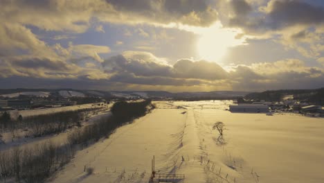 Vista-Aérea-Sobre-El-Cálido-Paisaje-Invernal-Iluminado-Por-La-Puesta-De-Sol-De-Hokkaido