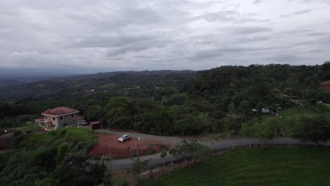 Aerial-dolly-in-flying-over-beautiful-house-on-green-hillside-surrounded-by-woods-on-a-cloudy-day-in-Costa-Rica
