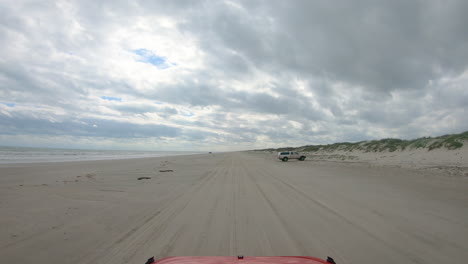 POV-of-a-slowly-driving-vehicle-on-the-beach-along-the-dunes-at-North-Padre-Island-National-Seashore-near-Corpus-Christi-Texas-USA-on-a-cloudy-day