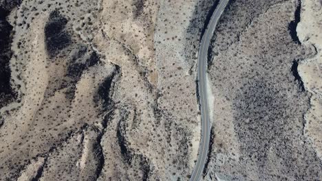 California-desert-road-with-few-vehicles-passing-by,-aerial-top-down-shot