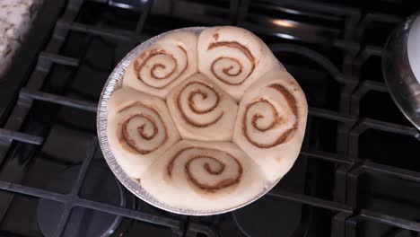 Raw-cinnamon-rolls-in-a-pan-on-the-stove-raising-before-baking---turning-to-raise-evenly-in-a-time-lapse