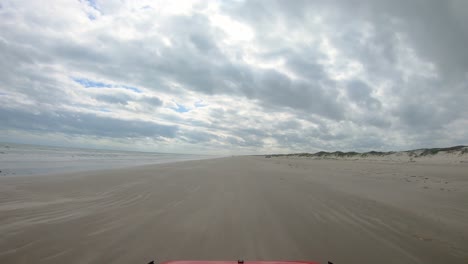 POV-thru-the-rear-window-of-vehicle-on-beach-between-surf-and-dunes-on-North-Padre-Island-National-Seashore-near-Corpus-Christi-Texas-USA-on-a-cloudy-day