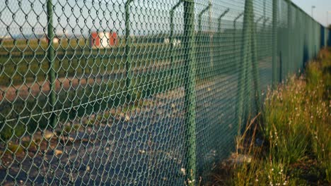A-double-chain-link-fence-around-a-secure-facility-then-the-suspicious-shadow-of-a-person-walking-along-the-fence-line
