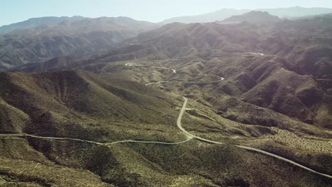 Endless-highway-road-winding-through-desert-mountain-landscape,-aerial-drone-shot