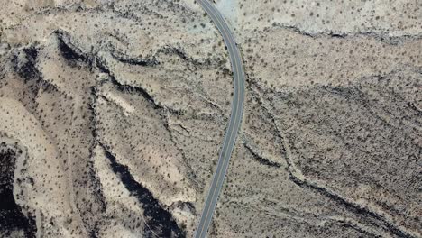 Lonely-vehicle-driving-on-desert-road-in-California,-aerial-top-down-shot