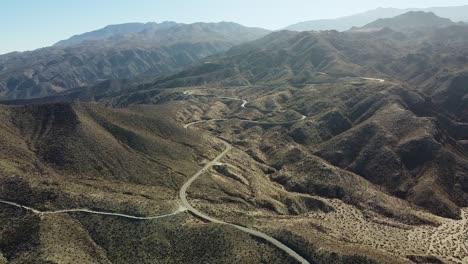 Desert-mountain-landscape-and-winding-highway-road,-aerial-drone-shot