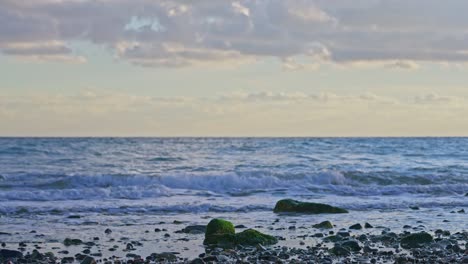 Rocky-beach-during-sunset-with-calming-waves