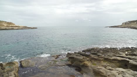 Ruhiges-Mittelmeerwasser-Umspült-Das-Ufer-Des-Steinstrandes-Il-kalanka-In-Malta