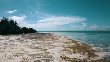 Wonderful-forwards-slowly-rise-up-drone-shot-of-one-guy-at-a-lonely-beach-at-midday-noon-time
