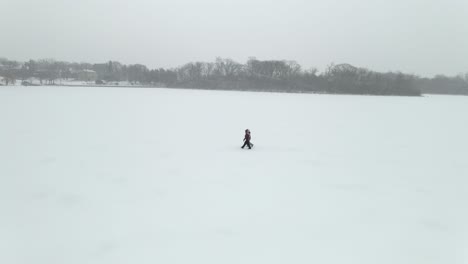 Zwei-Personen-Gehen-Während-Eines-Wintersturms-über-Einen-Zugefrorenen-See-In-Minnesota