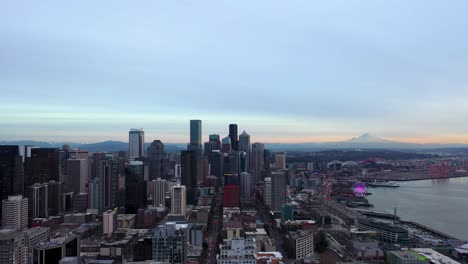 Breite-Antenne-Der-Wolkenkratzer-In-Der-Innenstadt-Von-Seattle-Mit-Dem-Mount-Rainier-Im-Hintergrund-In-Der-Abenddämmerung