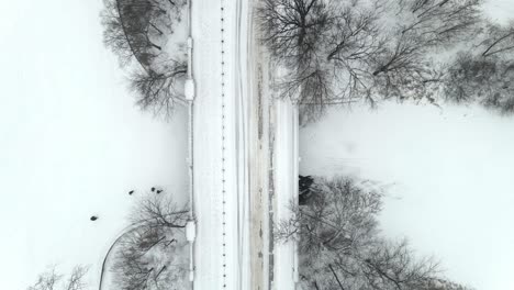 Aerial-perspective-of-a-car-driving-on-a-snowy-road