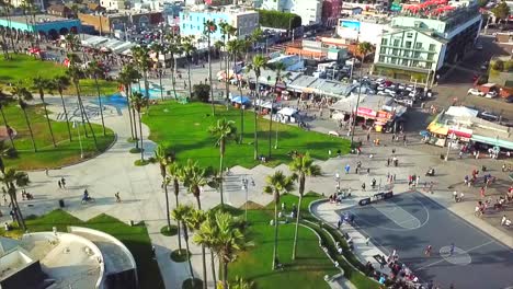 Drone-Volador-Sobre-Un-Día-Soleado-En-Venice-Beach-California-Palmeras,-Parque-De-Patinaje,-Bicicletas,-Ciudad-Y-Gente