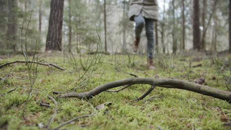 SLOW-MOTION:-Young-woman-walks-through-the-woods-and-steps-on-a-stick