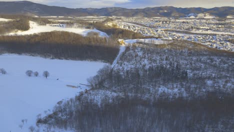 Aerial-View-Of-Natural-Landscape-Of-Hokkaido-In-Winter-With-Town-Of-Engaru-In-The-Distance
