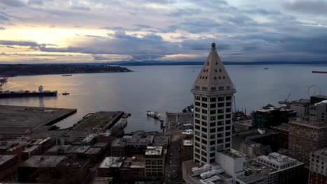 Aerial-of-Seattle's-Smith-Tower-overlooking-the-sun-setting-over-the-Puget-Sound