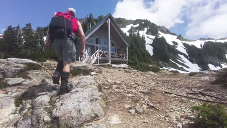 Hiker-Walking-toward-a-Mountain-Hut-on-Mount-5040,-Vancouver-Island,-Canada