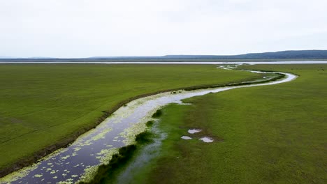 Ira-Lalaro-vast-open-wetland-plain,-lake,-stream-and-river-landscape-of-Lautem-district-in-Nino-Konis-Santana-National-Park,-Timor-Leste,-aerial-drone-flight-over-expansive-habitat