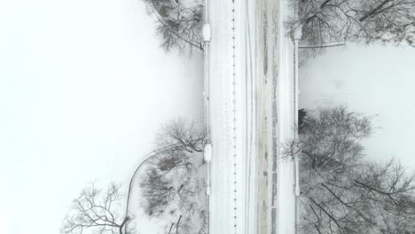 aerial-perspective-of-a-bridge-over-a-lake-covered-in-snow,-winter-landscape