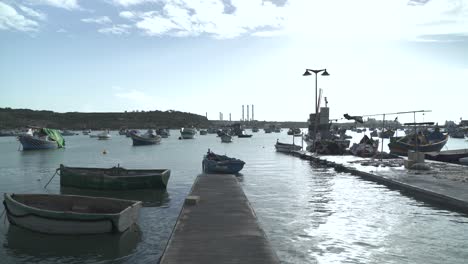 Old-Wooden-Boats-Floating-on-Calm-Mediterranean-Sea-in-Marsaxlokk-Fishing-Village
