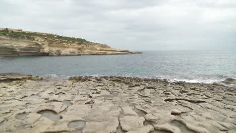 Playa-De-Piedra-Caliza-Il-kalanka-En-Malta-Con-Agujeros-En-El-Suelo-Llenos-De-Agua-En-Un-Día-Nublado
