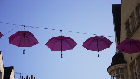 Pink-Umbrellas-hanging-street-decoration-in-European-village-slow-motion-4k-30p