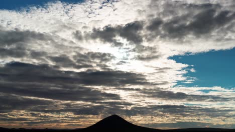 A-colorful-sunset-cloudscape-above-the-silhouette-of-a-butte-in-the-Mojave-Desert-in-this-wide-angle-time-lapse