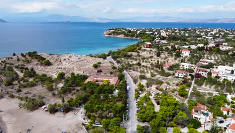 Aerial-drone-view-to-the-beautiful-beach-of-Moni-island,-next-to-the-village-Perdika-on-Aegina-island-with-turquoise-sea,-Saronic-Gulf,-Greece
