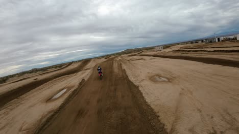 Motocross-athlete-jumps-a-motorcycle-over-a-dirt-track-on-trail-in-the-Mojave-Desert---aerial-view-in-slow-motion