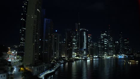 A-busy-capital-city-night-timelapse-where-the-skyscraper-skylights-spill-onto-the-river-that-is-bustling-with-boats-next-to-the-roads-that-are-busy-with-constant-moving-traffic