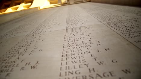 Nombres-De-Soldados-Caídos-En-Un-Cementerio-Conmemorativo-De-La-Guerra-En-Ypres,-Bélgica-Al-Atardecer,-Tiro-Manual-A-La-Deriva
