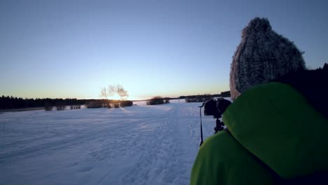 A-vlogger-holding-out-his-camera-to-film-himmself-at-sunset-in-a-winter-wonderland