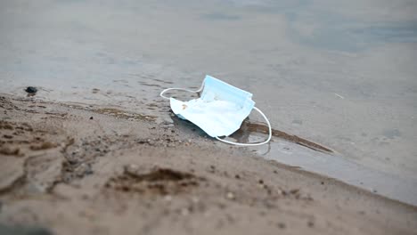 Discarded-surgical-face-mask-floating-on-the-river-on-a-cloudy-day--Static-shot