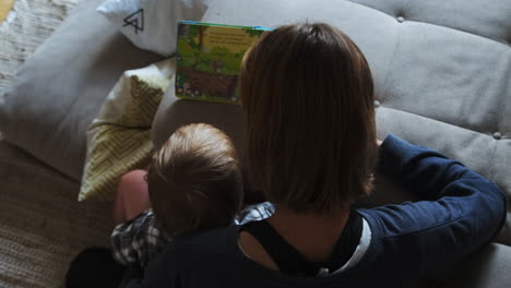 Junge-Und-Mutter-Lesen-Ein-Buch,-Während-Sie-Neben-Dem-Sofa-Sitzen