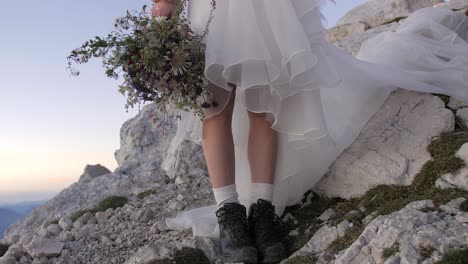 Braut-In-Den-Bergen-Im-Hochzeitskleid-Und-In-Den-Schwarzen-Stiefeln,-Die-Wildblumenblumenstrauß-Halten