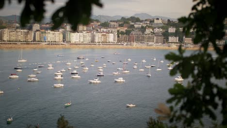 Boats-on-a-calm-harbor-during-sunset-on-a-bright-sunny-day-in-San-Sebastian-Spain-Europe-by-the-beach,-handheld-shot