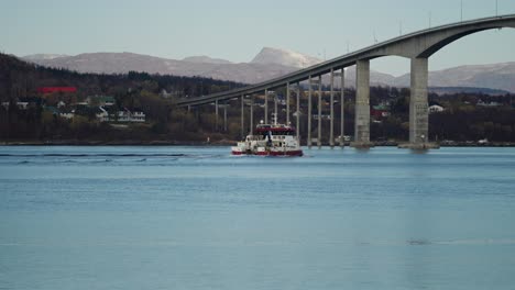 A-fishing-ship-passing-under-the-bridge-near-the-Senja-island,-Norway