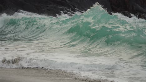 Mächtige-Wellen-Brechen-An-Die-Felsen-Und-Schwappen-über-Den-Sandstrand