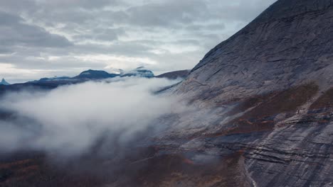 Ein-Dunkler-Berg-überragt-Die-Landschaft,-Herbstlicher-Wald-Bedeckt-Die-Ausläufer,-Weißer-Nebel-Schwebt-In-Der-Luft