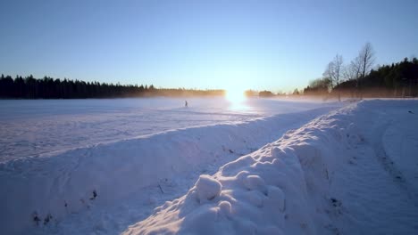 Den-Sonnenuntergang-über-Einem-Schneebedeckten-Hügel-Mit-Einer-Person,-Die-In-Der-Ferne-Läuft