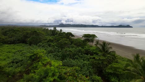 Drone-Shot,-flight-over-green-trees-to-the-beach-and-sea-in-Costa-Rica