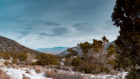 View-of-a-high-desert-valley-and-the-rocky-mountains-beyond-as-seen-from-a-canyon-in-winter---time-lapse