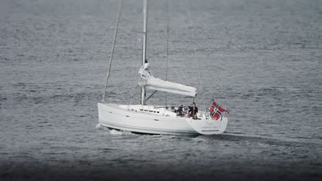 Ein-Segelboot-Mit-Gefaltetem-Segel-Und-Norwegischer-Flagge-Fährt-Unter-Den-Motor