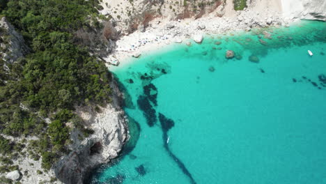 Aerial-drone-video-of-tropical-paradise-beach-and-sea-cliffs-in-the-mediterranean,-Costa-Azzurra,-Sardinia,-Italy