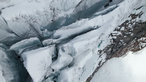 Aerial-close-up-view-of-the-crevasses-on-the-edge-of-a-large-glacier-on-a-sunny-day-in-winter-in-the-Alps