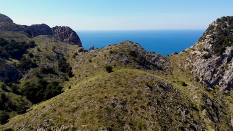 Drone-push-in-shot-over-Mallorca-coastal-mountains-with-azure-sea-background