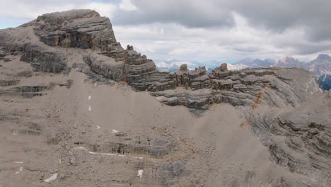 Aerial-view-of-rocky-mountain-summit-formation-against-cloudy-sky-in-background