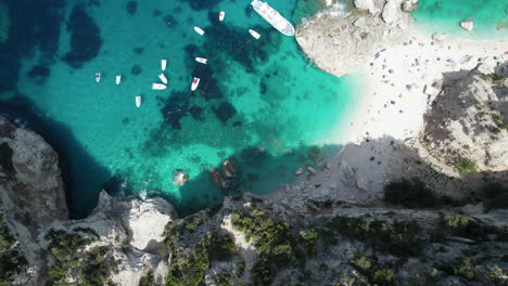 Drohnenvideo-Aus-Der-Luft-Von-Oben-Nach-Unten-Vom-Türkisfarbenen-Strand-Des-Tropischen-Paradieses-Im-Mittelmeer,-Sardinien-Mit-Booten