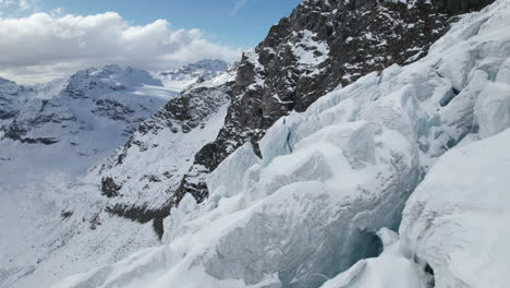 Aerial-close-up-view-of-the-cracks-of-the-face-of-a-large-glacier-on-a-sunny-day-in-winter-in-the-Alps