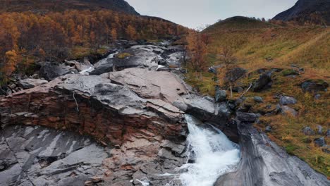 An-aerial-view-of-the-wild-river-rushes-in-the-narrow-rocky-riverbed-through-the-autumn-landscape